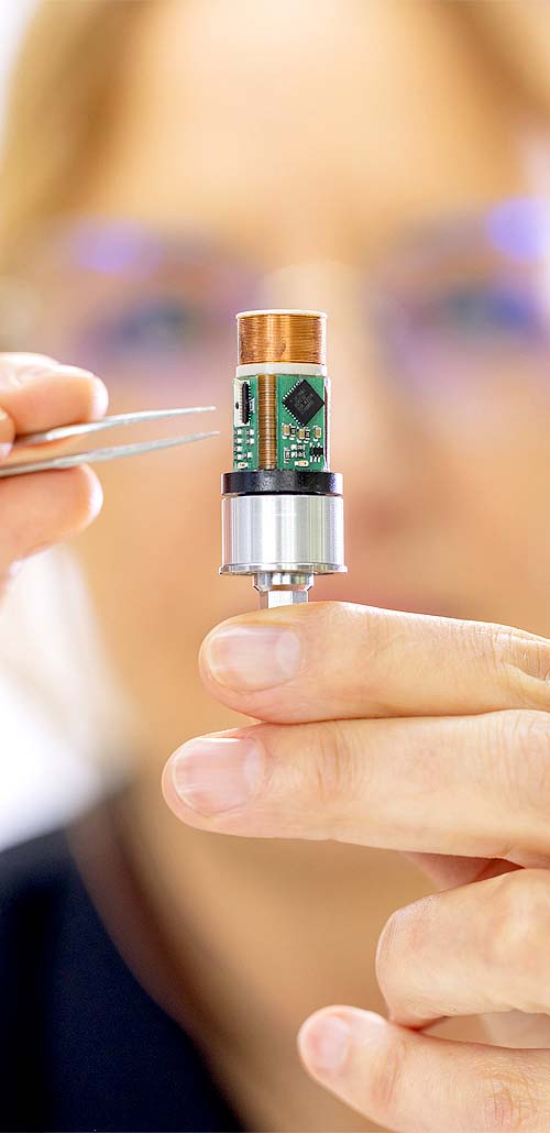 Frau, unscharf im hintegrund hält ein elektronikbauteil mit pinzette